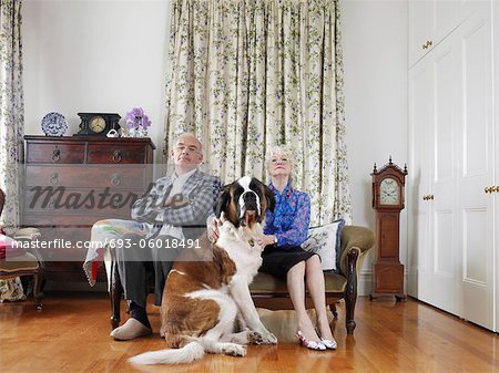 Senior couple posing in living room with dog