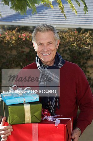 Senior man holding presents outside