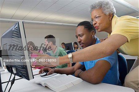 Teacher helping student in computer class
