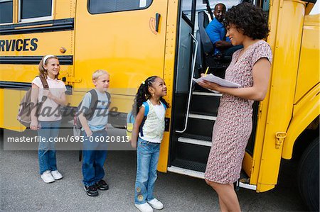 Teacher Loading Elementary Students on School Bus