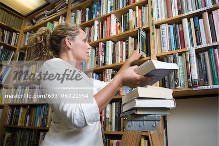 Female librarian putting books on shelves