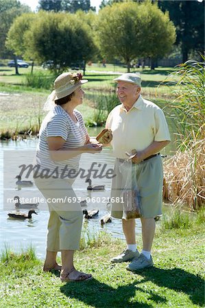 Senior couple standing in front of stream, talking