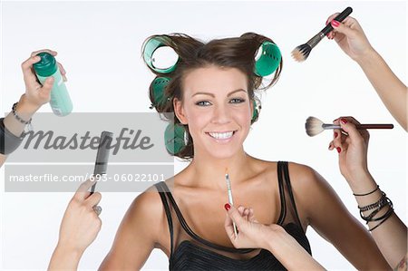 Woman in rollers , with cosmetics products on hand