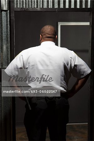 Security guard stands with hands on hips rear view