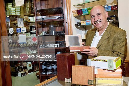 Portrait of a happy owner showing cigar boxes in store