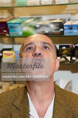 Mature man in tobacco store blowing smoke