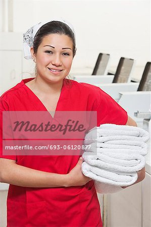 Portrait of a happy female employee in red uniform holding towel