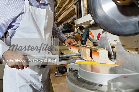 Midsection of young craftsman cutting wood with circular saw