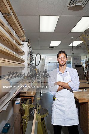 Portrait of a happy skilled worker standing with arms crossed in workshop