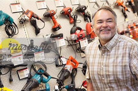 Happy mature hardware store owner looking away