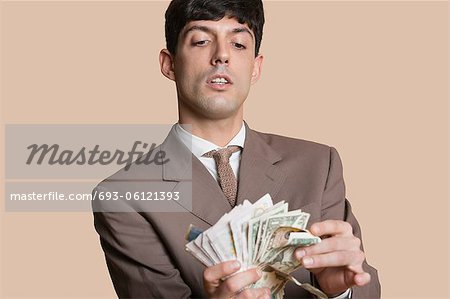 Young businessman counting money over colored background