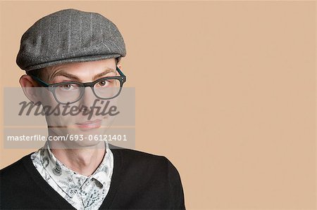 Portrait of a mid adult man wearing retro glasses and cap over colored background