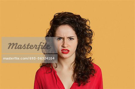 Portrait of angry young woman frowning over colored background Portrait of angry young woman frowning over colored background
