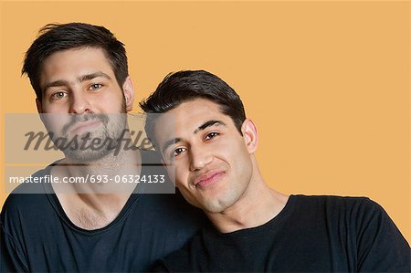 Portrait of young male friends over colored background