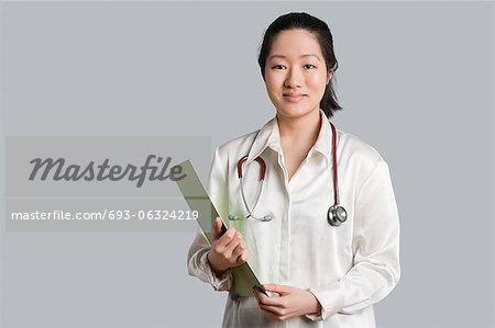 Portrait of a young Asian female doctor with a clipboard over gray background