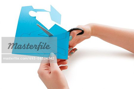 Woman's hand cutting a paper stick figure over white background