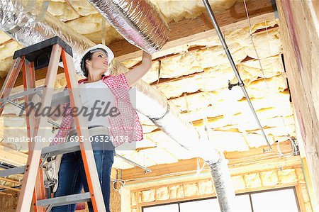 Low angle view of female worker working on incomplete ceiling
