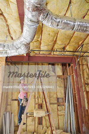 Female architect moving up the ladder to check incomplete ceiling