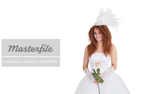 Portrait of elegant brunette in wedding dress holding rose over white background
