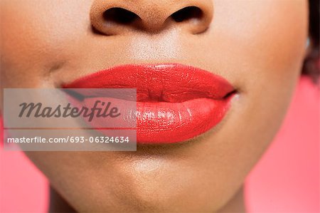 Close-up view of an African American woman's red lips over colored background