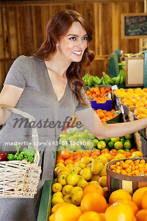 Happy young woman shopping in supermarket for fruits