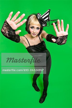 Portrait of young woman posing with fingerless gloves and headdress over green background