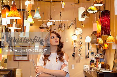 Beautiful young woman browsing for lights with arms crossed in store
