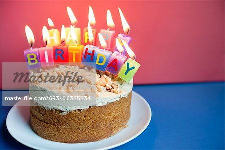 Close-up of candles burning on birthday cake over colored background