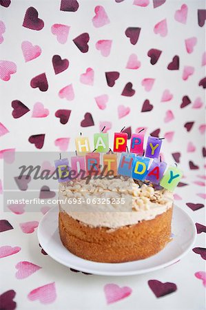 Close-up of birthday cake with candles over heart shaped background