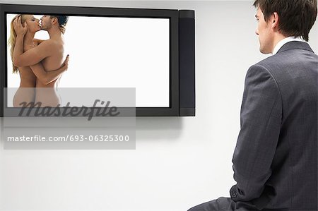 Businessman watching erotic naked couple on flat screen