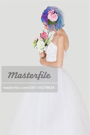 Side view of young woman in wedding dress with dyed hair against gray background