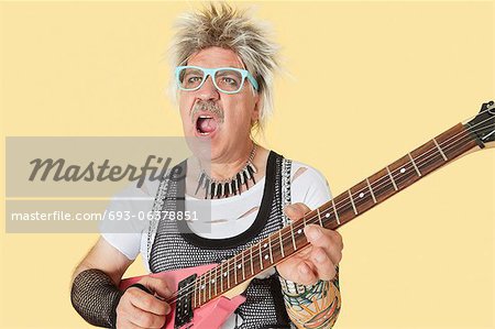 Senior male punk musician playing guitar over yellow background