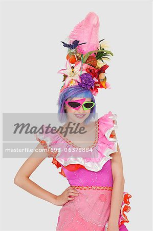 Portrait of beautiful young woman in Brazilian outfit and funky glasses over gray background