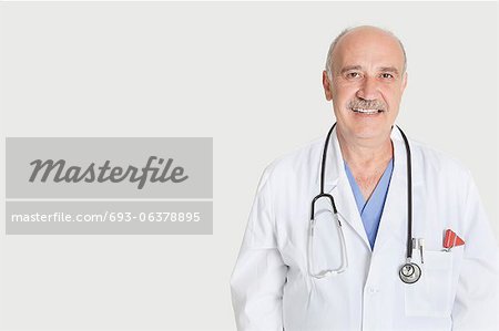 Portrait of happy senior medical practitioner over gray background