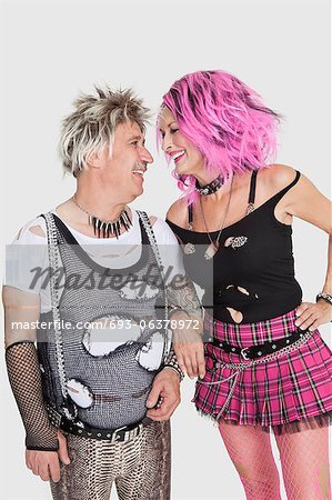 Happy senior punk couple looking at each other over gray background