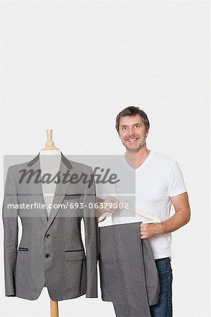 Portrait of mature man standing next to tailor's dummy over gray background