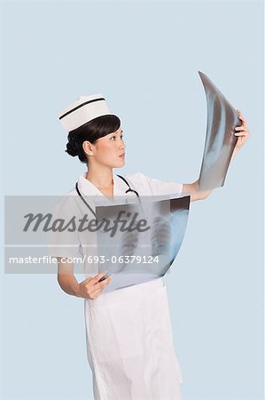 Female doctor analyzing x-ray reports over light blue background