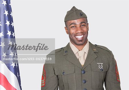 Portrait of a male soldier smiling with American flag, Studio Shot on gray background