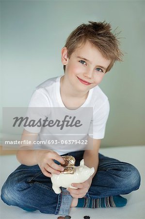 Portrait of young boy putting coin in piggy bank