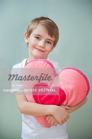 Portrait of little boy holding heart shape cushion