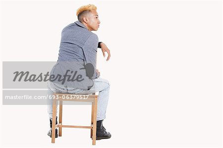 Back view of teenage boy sitting on chair as he looks away over gray  background - Stock Photo - Masterfile - Premium Royalty-Free, Code:  693-06379517