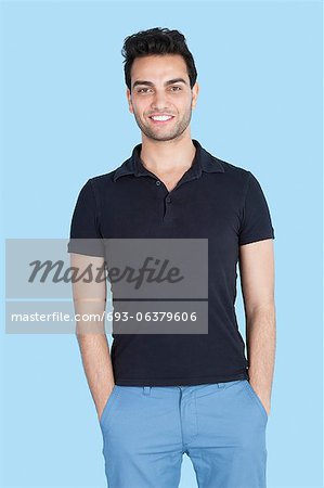 Portrait of a handsome man with hands in pockets over blue background