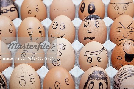 Funny faces on painted on brown eggs arranged in carton