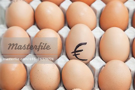 Euro sign on egg surrounded by plain brown eggs in carton Euro sign on egg surrounded by plain brown eggs in carton