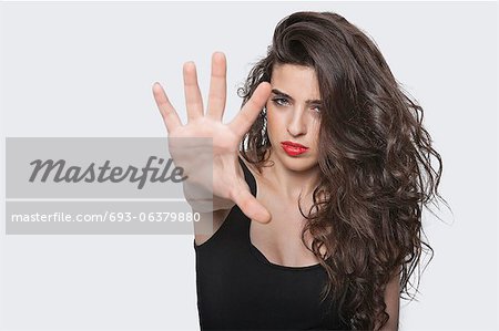 Portrait of a young female gesturing stop sign over gray background
