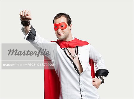 Young man wearing superhero costume against gray background