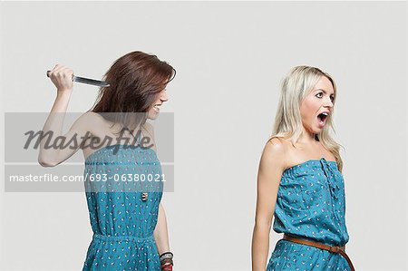 Friend stabbing young woman in similar jump suits from behind
