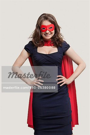 Portrait of a young woman in superhero costume over gray background