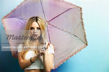 Portrait of a young woman with umbrella against blue background