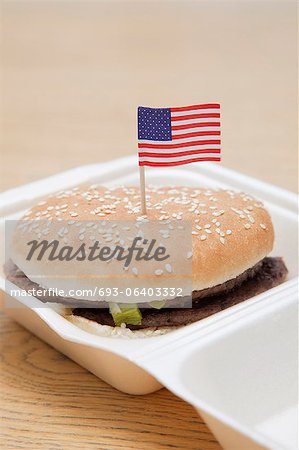 Grilled hamburger with American flag decoration on wooden surface